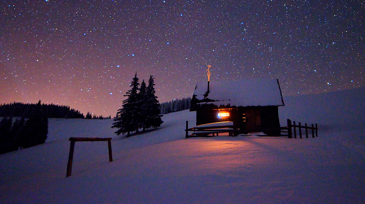 Kleines Holzhaus in einer winterlichen Landschaft in der Abenddämmerung